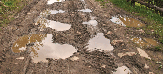 Motor grader on a dirt road during a Perma-Zyme application