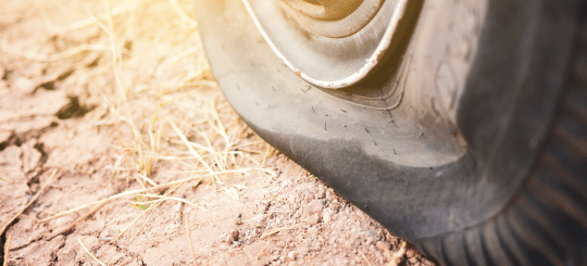 Flat heavy duty equipment tire on a dry, unpaved road