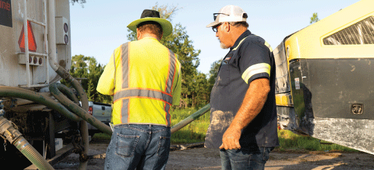 Two men preparing heavy-duty equipment to treat a project site with Perma-Zyme