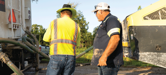 Two men preparing heavy-duty equipment on a jobsite