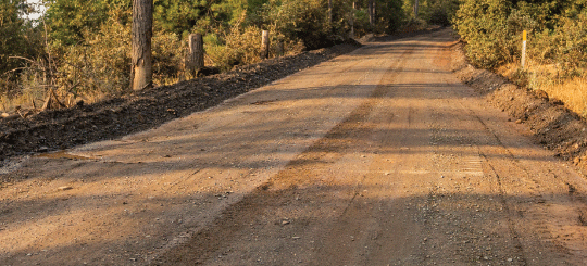 Dirt Perma-Zyme treated road with setting sun casting shadows