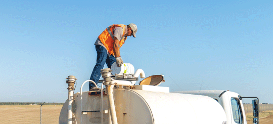 Man pouring Perma-Zyme into a water truck