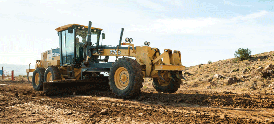 Motor grader grading a dirt public road