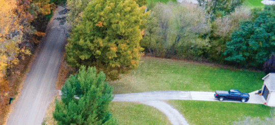 Aerial shot of residential driveway and property connecting to a Perma-Zyme treated road