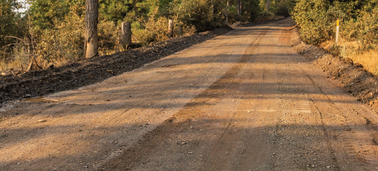 Sunset casting shadows on a dirt public road